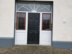 una puerta negra y ventanas en un edificio blanco en Ground Floor Slievemore Apartment, en Bellanasally