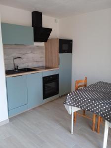 cocina con armarios azules, mesa y fregadero en Appartement PLOEMEUR-Fort Bloqué, en Ploemeur