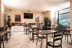 特倫托的住宿－布里科斯里昂酒店，餐厅设有桌椅和平面电视。