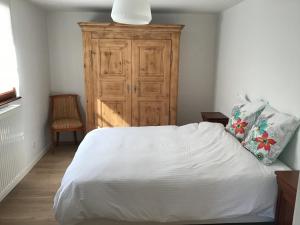 a bedroom with a white bed and a wooden cabinet at L'atelier du gîte bleu in Willgottheim