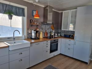 a kitchen with white cabinets and a sink and a window at T-R Huset i Hellosan in Bøstad