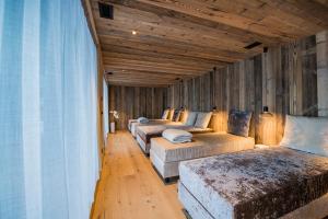 three beds in a room with wooden walls at Hotel Laurin in Dobbiaco