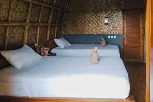 a couple of beds in a room at Villa Bambu Rinjani & Restaurant RedPartner in Senaru