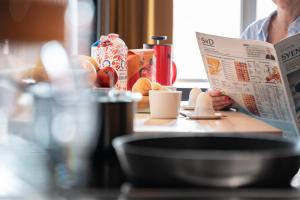 una persona seduta a un tavolo a leggere un giornale di Mornington Hotel Bromma a Stoccolma