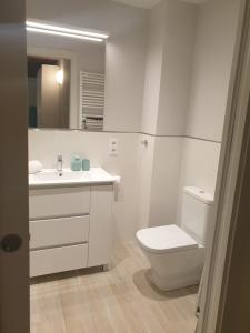 a white bathroom with a toilet and a sink at Basses TOP in Vic