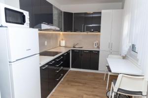 a kitchen with black cabinets and a white refrigerator at Apartmani ORION - Kasiopeja in Vinkovci