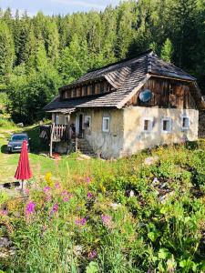 ein altes Haus inmitten eines Feldes mit Blumen in der Unterkunft Obiralmhütte Fladung in Bad Eisenkappel