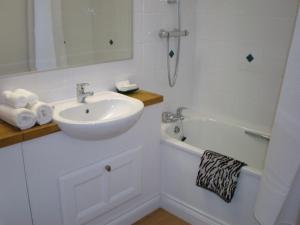 a white bathroom with a sink and a bath tub at Higher Faugan in Penzance