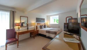 a bedroom with a bed and a desk and a television at Higher Faugan Parc in Penzance