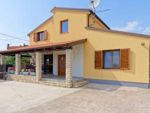 a yellow house with a porch and windows at Apartment Larissa in Višnjan