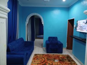 a living room with blue walls and blue chairs at Homestay Dalia, Beseri, Perlis in Kangar