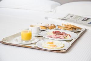 bandeja con alimentos para el desayuno y un vaso de zumo de naranja en Executive Inn Boutique Hotel, en Brindisi