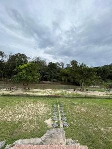 un campo de hierba con un cuerpo de agua y árboles en Sofia Adila Homestay en Hulu Langat
