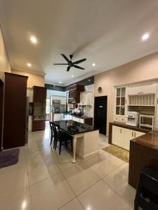 een grote keuken met een tafel en een plafondventilator bij Sofia Adila Homestay in Hulu Langat
