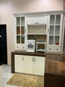 cocina con armarios blancos y microondas en Sofia Adila Homestay en Hulu Langat
