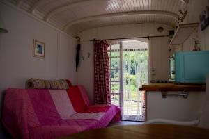 Una sala de estar con un sofá rosa y una puerta corrediza de vidrio. en pipowagen Blagour gelegen aan waterbron, en Lachapelle-Auzac