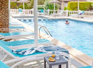 una piscina con sillas y una mesa con bebidas en Roquetes Rooms - Formentera Break en Es Pujols