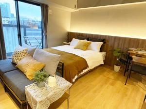 a bedroom with a bed and a couch and a window at R Hotel Namba in Osaka