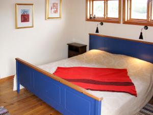 um quarto com uma cama azul e um cobertor vermelho em Holiday Home Fågelkärr Sjöstugan by Interhome em Gränna