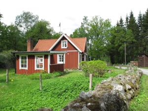 a red house with a stone wall in front of it at Holiday Home Åkekvarn Snärjet - B in Olofström