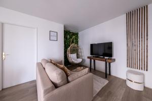 ein Wohnzimmer mit Sofa und Fernseher in der Unterkunft Sérénité proche Disneyland in Serris