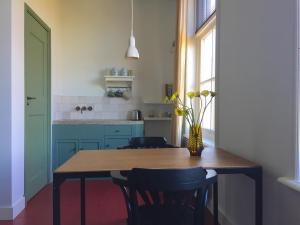 una cocina con una mesa de madera con sillas y un jarrón de flores en B&B de Bels, en Harich