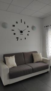 un orologio su un muro bianco sopra un divano di Donatella House a Piove di Sacco