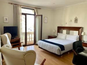 Un dormitorio con una cama, un televisor y una silla. en Balcón Al Mar, en Valencia