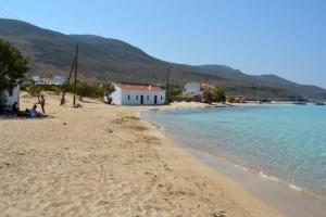 a beach with a white house and the water at Donusa Beach House - Etheras properties in Diakofti