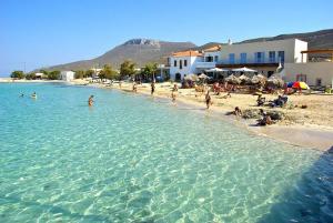 a group of people swimming in the water on a beach at Donusa Beach House - Etheras properties in Diakofti