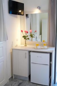 a bathroom with a white vanity with a vase of flowers at Prince Studios in Sami