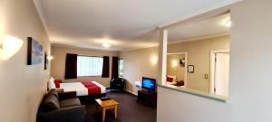 a hotel room with a bed and a television at Parklands Motor Lodge Timaru in Timaru