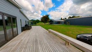 una terraza de madera con un banco junto a una casa en Full holiday home to yourself, up to 21 guests en Atiamuri