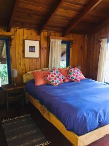 a bedroom with a bed with blue sheets and pillows at Hostel Raíz in Pucón