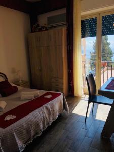 a bedroom with a bed and a chair and a window at B&B Antonella in Taormina