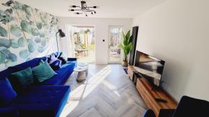 uma sala de estar com um sofá azul e uma televisão de ecrã plano em Beautiful 2bed house with garden, walking distance to town - FREE parking em Glasgow