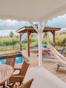 a patio with a hammock and a pool at Les Villas Mandju in Sainte-Rose