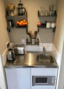 a small kitchen with a sink and oranges on shelves at Rodeen self-catering apartment in Castletownbere