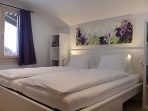 a bedroom with a large white bed with a painting on the wall at Apartment Schwendi 3 by Interhome in Grindelwald