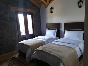 2 Einzelbetten in einem Zimmer mit Fenster in der Unterkunft Chri Chri Guesthouse in Përmet