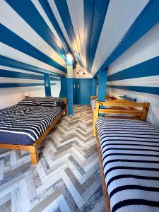 two beds in a room with a blue ceiling at Petite maison de vacance très proches de la mer in Saint Malo