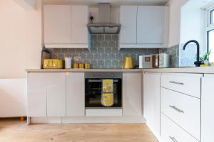 een keuken met witte kasten en een oven bij Hare Cottage in Abergavenny