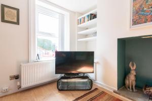 a living room with a flat screen tv next to a fireplace at Hare Cottage in Abergavenny