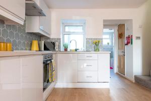 a kitchen with white cabinets and a counter top at Hare Cottage in Abergavenny