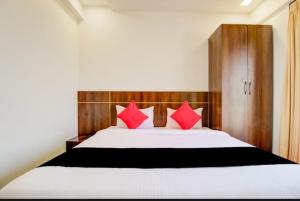a bedroom with a large white bed with red pillows at Hotel rio inn in Trimbak