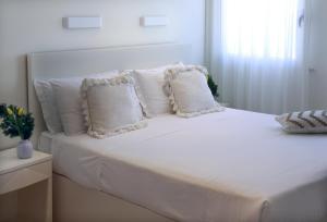 a white bed with white pillows in a bedroom at Piccadilly Rooms Restaurant and Beach in Santa Maria al Bagno