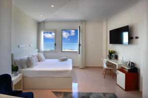 een slaapkamer met een bed, een bureau en 2 ramen bij Piccadilly Rooms Restaurant and Beach in Santa Maria al Bagno