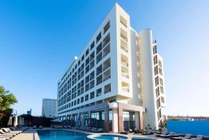 a large white building with a pool of water in front of it at TRYP by Wyndham Lisboa Caparica Mar in Costa da Caparica