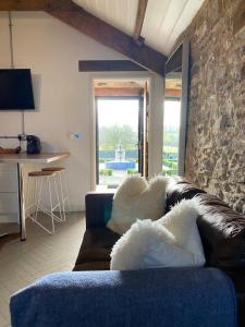 a living room with a couch and a stone wall at Gardener's Cwtch, Llwynhelig Manor in Llandeilo