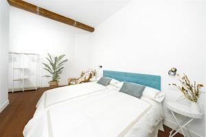 ein weißes Schlafzimmer mit einem weißen Bett und einem blauen Kopfteil in der Unterkunft SANTANDER CENTRO in Santander